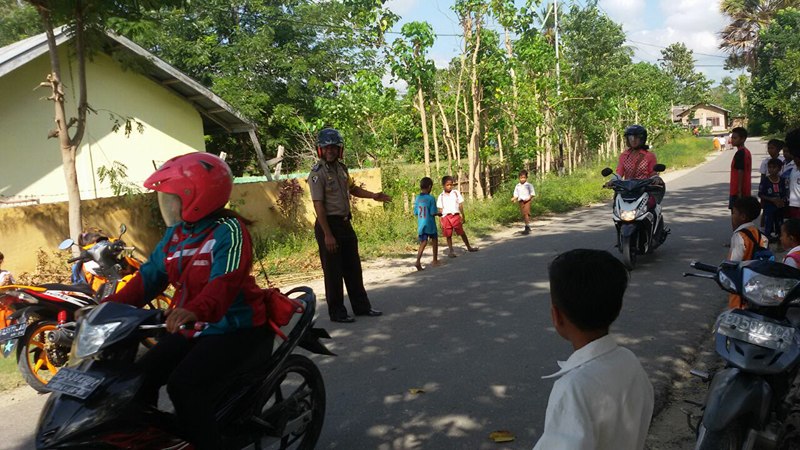 Bhabinkamtibmas Mauliru Sumba Timur Mengatur Lalin dan Bantu Siswa TK Seberangi Jalan Saat Pulang Sekolah